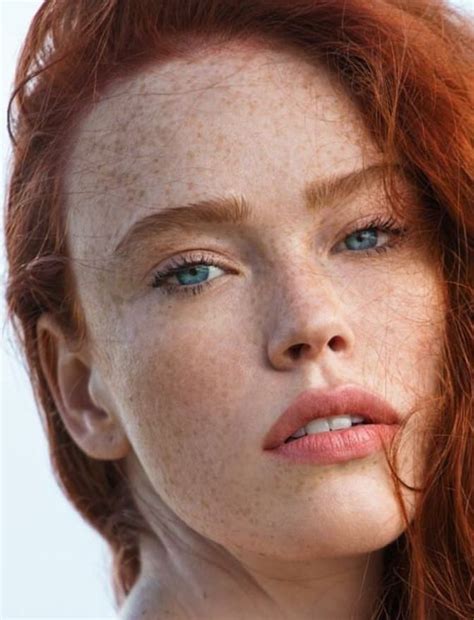 a woman with freckled hair and blue eyes looks into the distance while ...