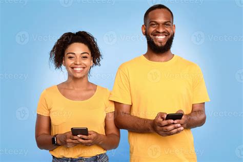 Affectionate young African American couple using mobile phones, surfing