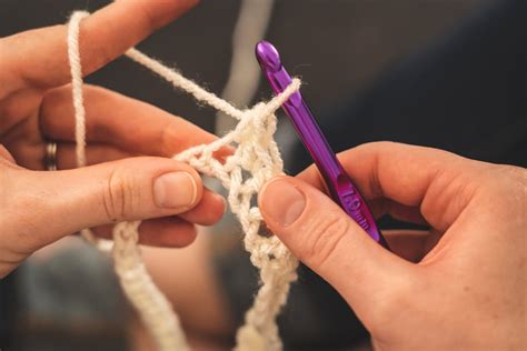 person holding purple crochet hook  white yarn  stock photo