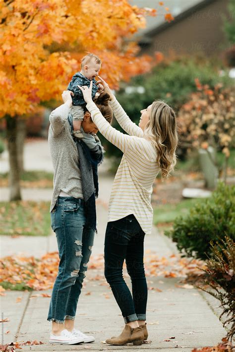 "Lesbian Moms Walking With Baby Daughter On Sidewalk In The Fall." by