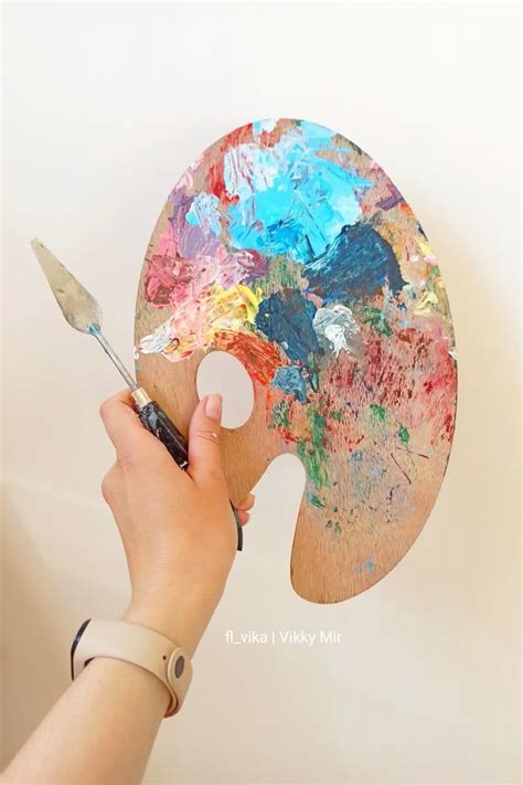 Палитра и мастихин в руке художника. Palette and palette knife in the ...