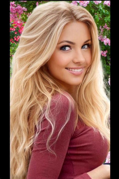 a beautiful blonde woman with long hair posing for a photo in front of