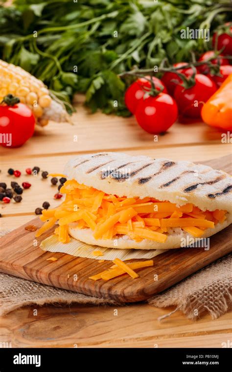 Arepa with cheddar cheese on a cutting board Stock Photo - Alamy