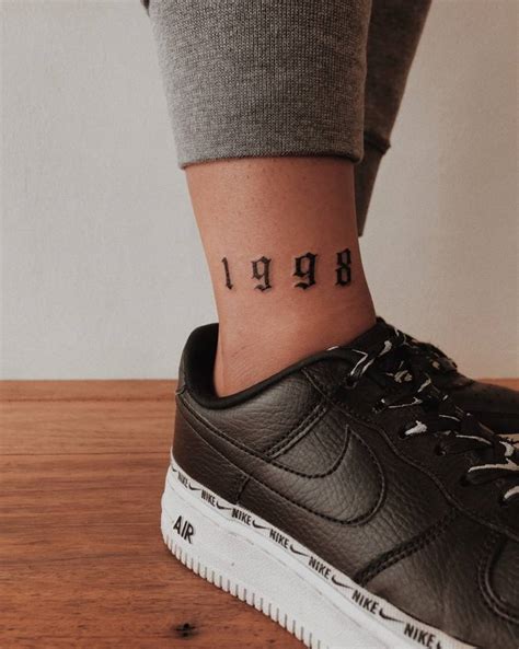 "1998" lettering tattoo on the ankle.