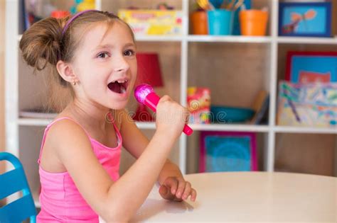 Little Girl Singing into a Toy Microphone Sitting Stock Image - Image ...