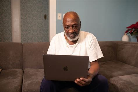 Download Old Black Man Using Laptop On Couch Wallpaper | Wallpapers.com