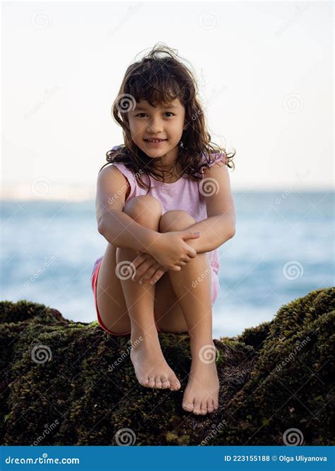 Young Girl Sitting on the Rock Near the Ocean and Smiling. Happy
