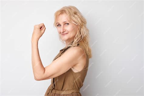 Портрет уверенной в себе 50-летней женщины, показывающей бицепсы ...