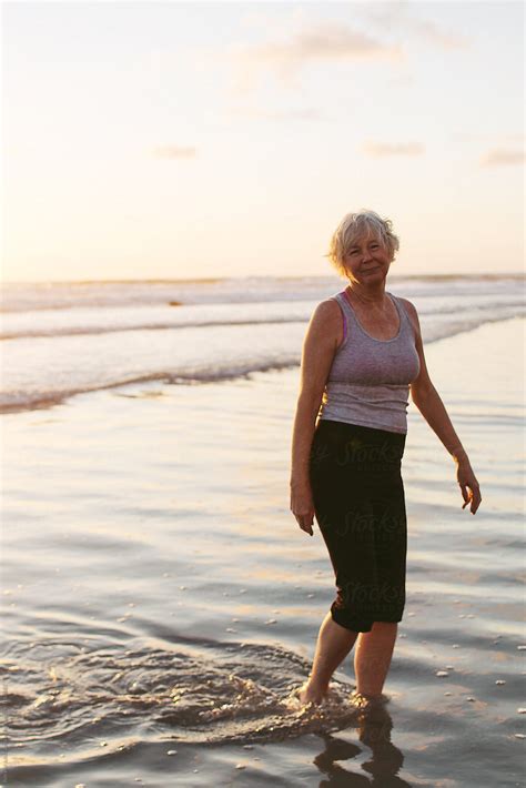 "Vibrant Mature Woman Enjoying Herself On The Beach At Sunset" by