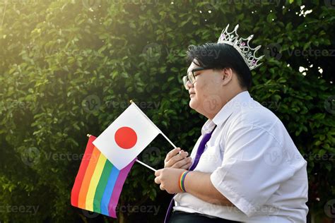 Japanese boy holds rainbow flag and Japan national flag and wears crown