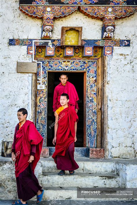 Asian monks walking out temple doorway — bhutan, indoors - Stock Photo