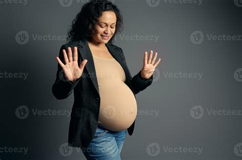 Beautiful pregnant woman expecting a baby, showing number nine with her