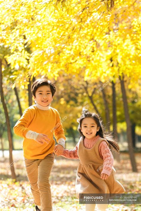 Adorable feliz asiático hermano y hermana corriendo juntos en otoño