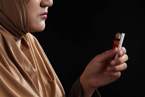 Close up young muslim woman holding a cigarette on black background ...