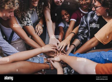 Happy teenagers putting their hands together in a huddle. Group of ... 
