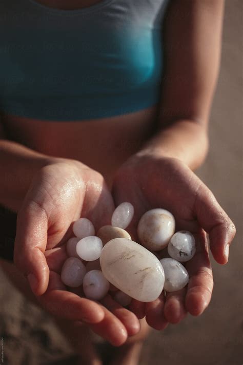 "Tan Girl Holding Seaglass Stones In Her Hands On The Beach" by Stocksy