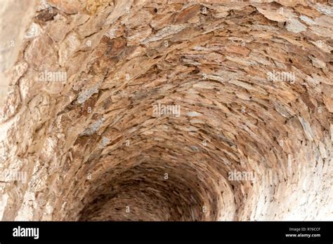 Tunnel made of stone with natural light coming in Stock Photo - Alamy