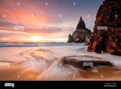 Golden reflections of the cliffs on Praia da Ursa beach bathed by ocean