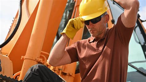 Heavy Construction Equipment Caucasian Operator Wearing Yellow Hard Hat For a Head Safety