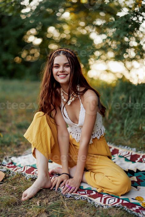 A young beautiful hippie woman sits on the ground in the fall in eco