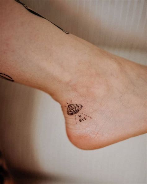FIne line UFO tattoo on the ankle.