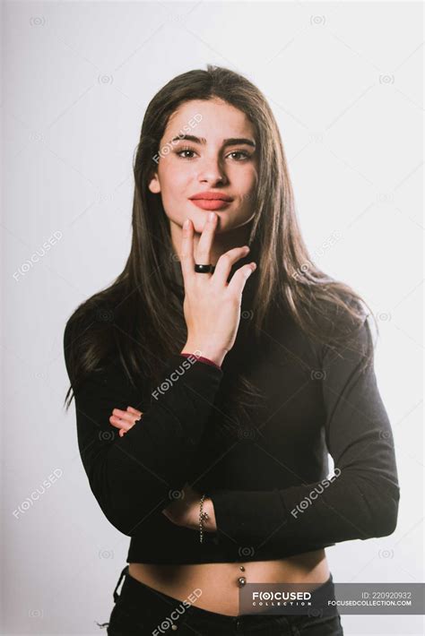 Sexy girl in black outfit with belly piercing posing on grey background