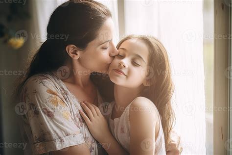 Mother hugs and kisses daughter on the cheek while smiling. 24949288