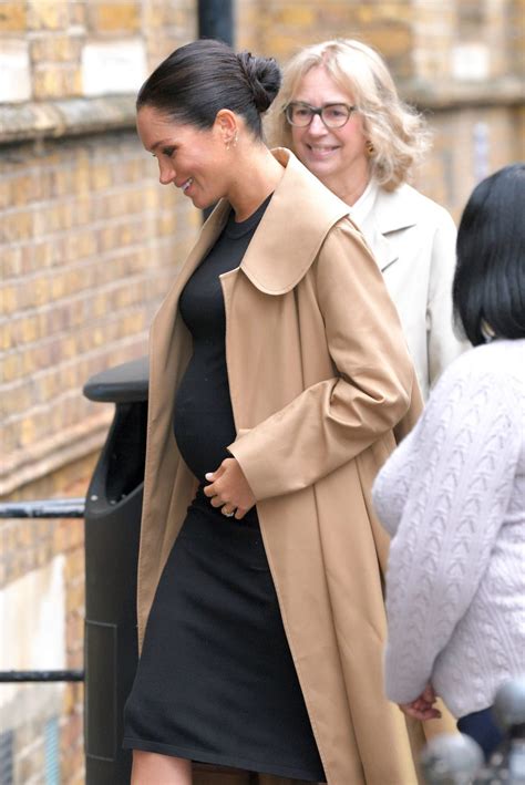 Meghan cradles baby bump in fitted black dress as she’s given four