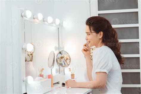 Amazing young woman doing her makeup in front of mirror. Portrait of