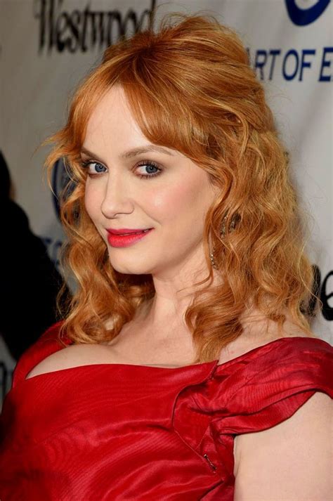a woman with red hair and blue eyes wearing a red dress at an awards event
