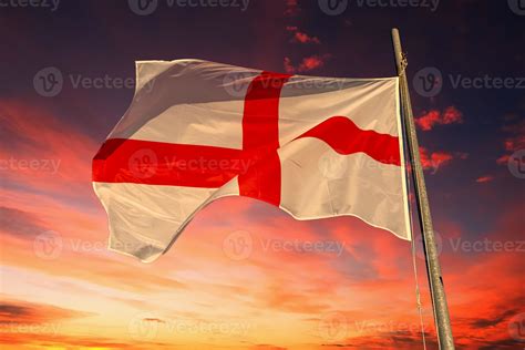 waving english flag red cross on white isolated on dramatic reds sky