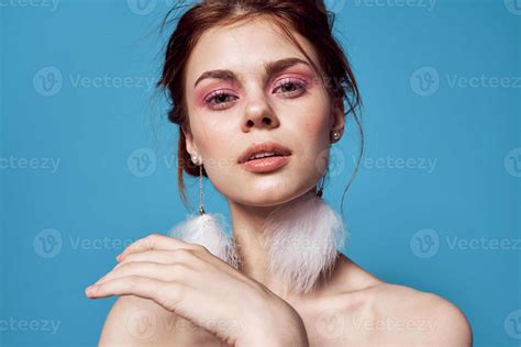 pretty woman naked shoulders and fluffy earrings bright makeup blue