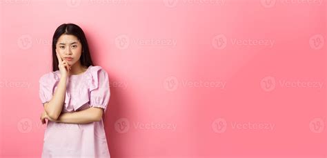 Bored asian teen girl look indifferent at camera, lean face on hand in