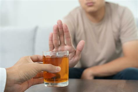 man refuses say no and avoid to drink an alcohol whiskey , stopping
