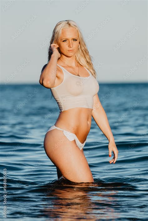 Sexy woman in wet t-shirt playing on water at beach over sea. Summer ...