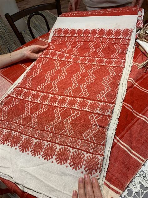 two women are working on an old red and white cloth
