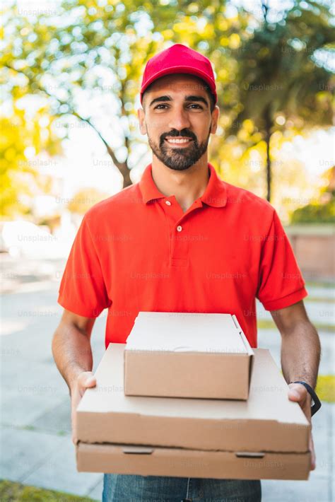 Portrait of a delivery man with cardboard pizza box outdoors in street