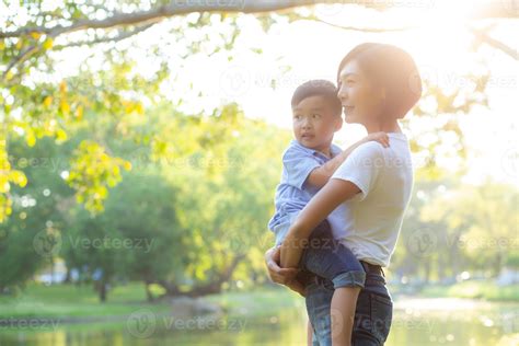 Beautiful young asian mother carrying little boy in the park, asia