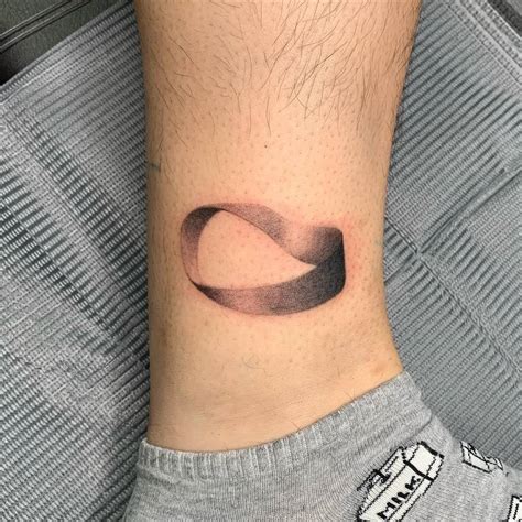 Micro-realistic möbius strip tattooed on the ankle.