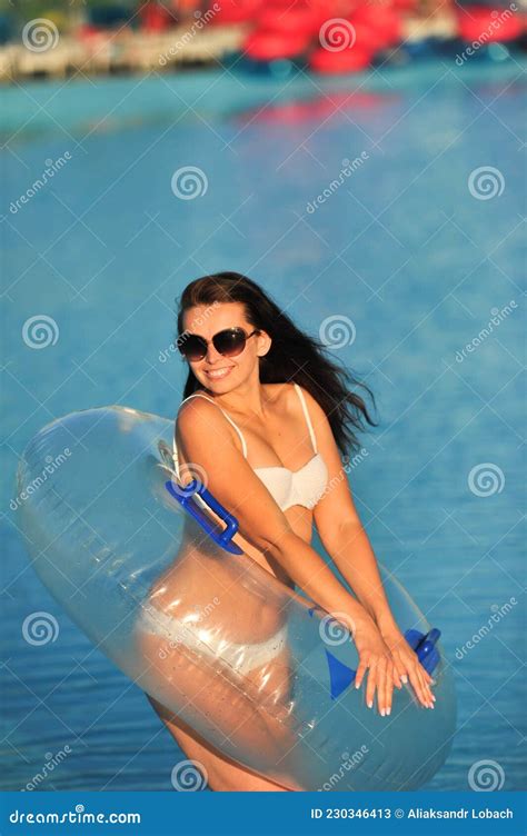 A Woman in a White Bathing Suit with an Inflatable Circle in a Water ...