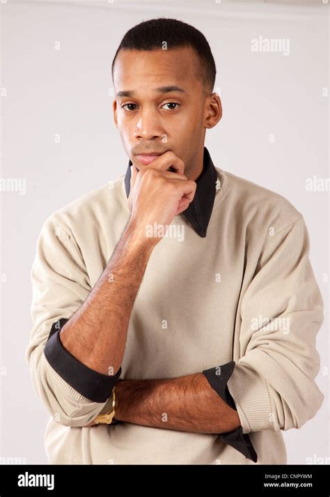 Handsome young black man with pensive expression and hands on his chin ...