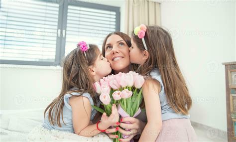 Happy mother's day concept. Little daughters twins kiss their mother