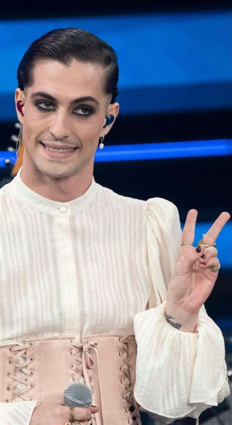 the man is making a peace sign while wearing a corset and holding a ...