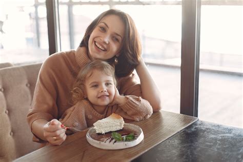 Happy mother and daughter eating dessert in cozy cafe · Free Stock Photo