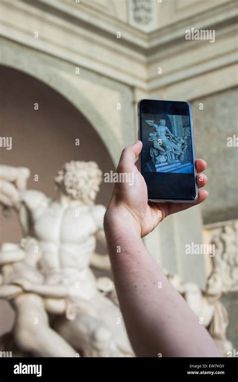 A tourist is taking a picture of the Sculpture of the Laocoön group ...