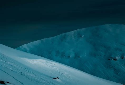 Snowy mountain ridge under dark night sky · Free Stock Photo