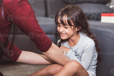 Caucasian little girl tickled by mother in living room. People