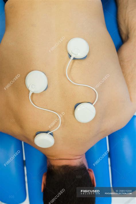 Man lying on chest with electrode pads on back in clinic — relief