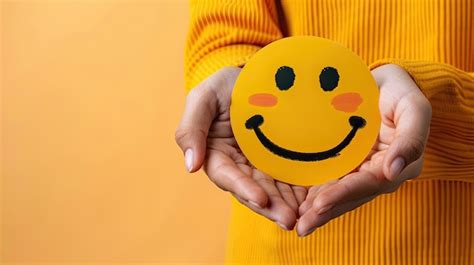 Premium Photo | Hands Holding Smiling Face Emoji on Yellow Background