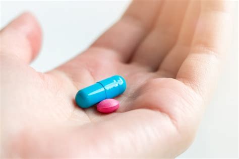 Premium Photo | Blue and pink pill capsule on the female palm on white background ...